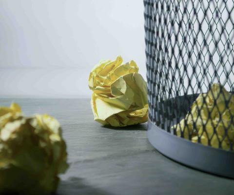 Crumpled paper ball next to garbage can