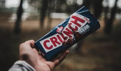 Greenwashing - Hand Holding Nestle Crunch Bar