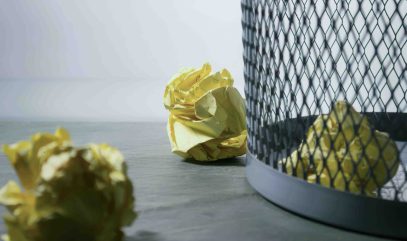 Crumpled paper ball next to garbage can